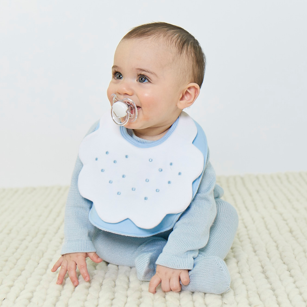 Baby boy wearing blue terry bib with dot embroidery